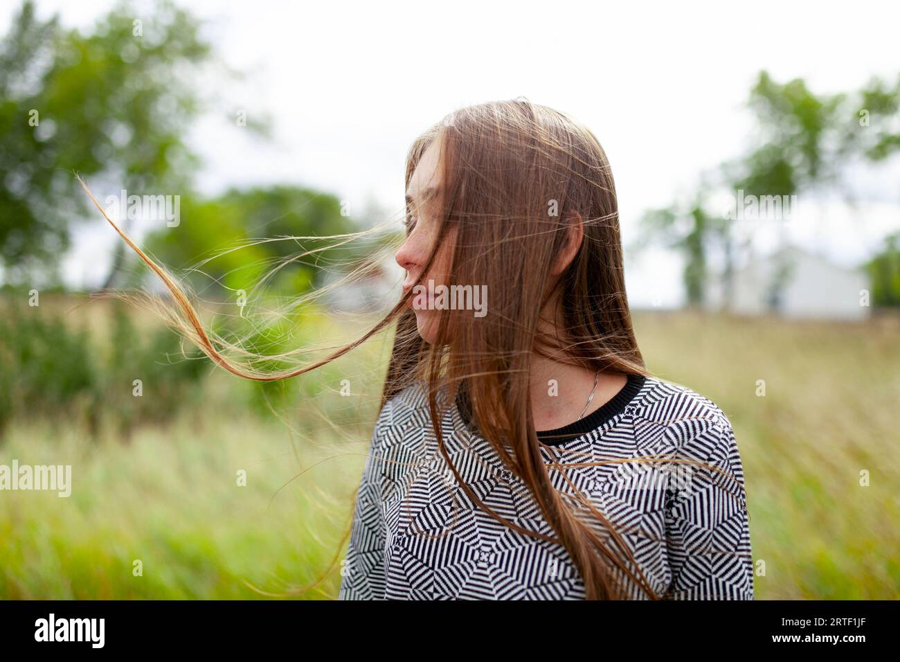 Giovane donna bionda con i capelli in slitta in campo Foto Stock