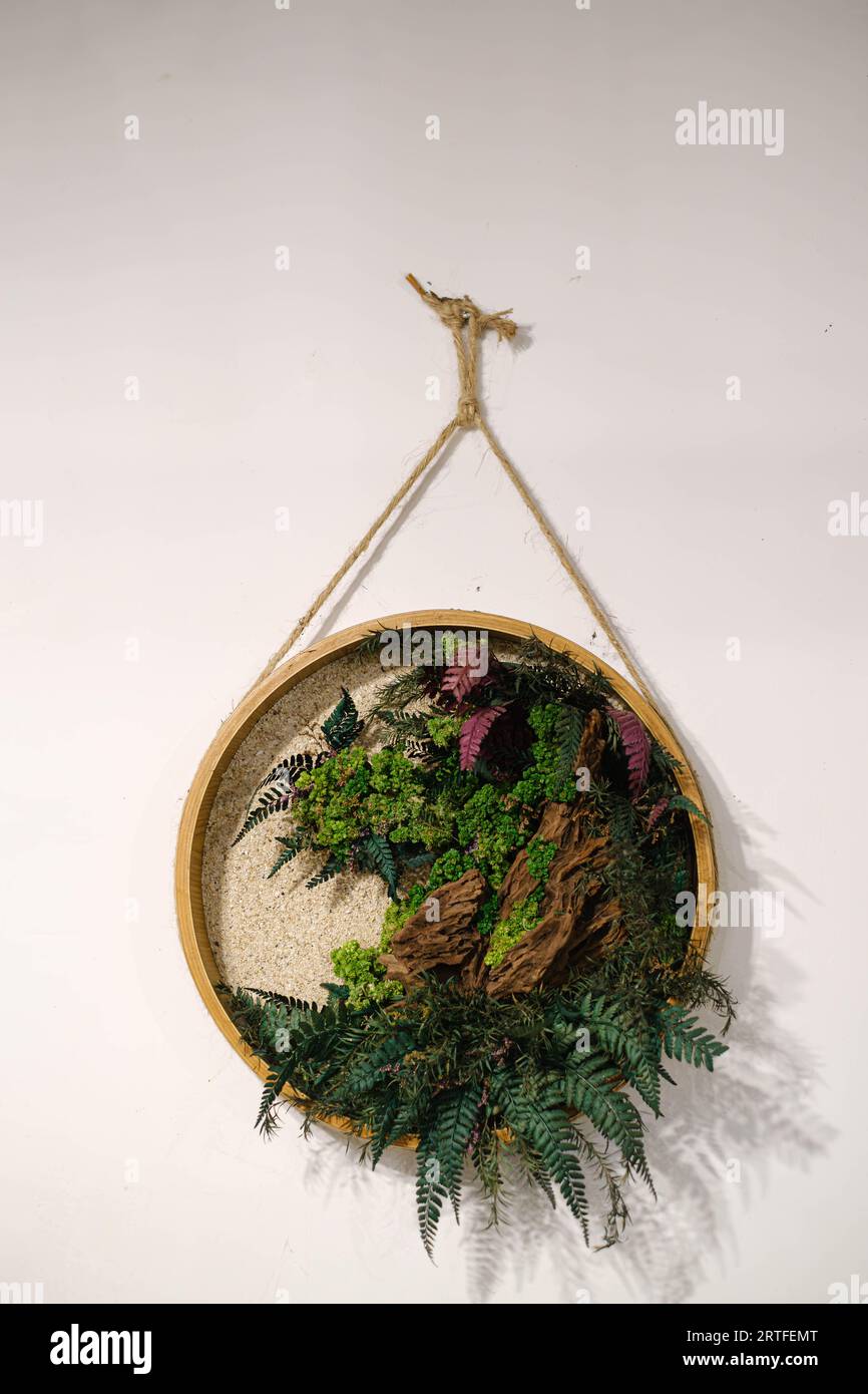 Decorazioni a parete in legno arrotondate con molte foglie e rocce per portare l'atmosfera tropicale in un'area interna Foto Stock