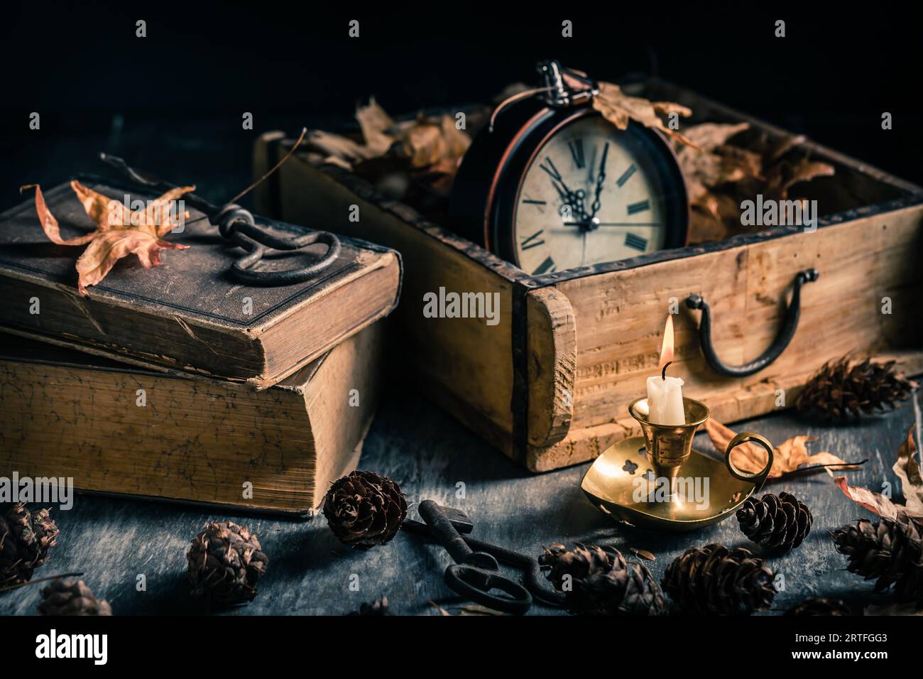 Natura morta d'epoca con libri antichi, orologio e candela. Halloween e concetto occulto. Foto Stock