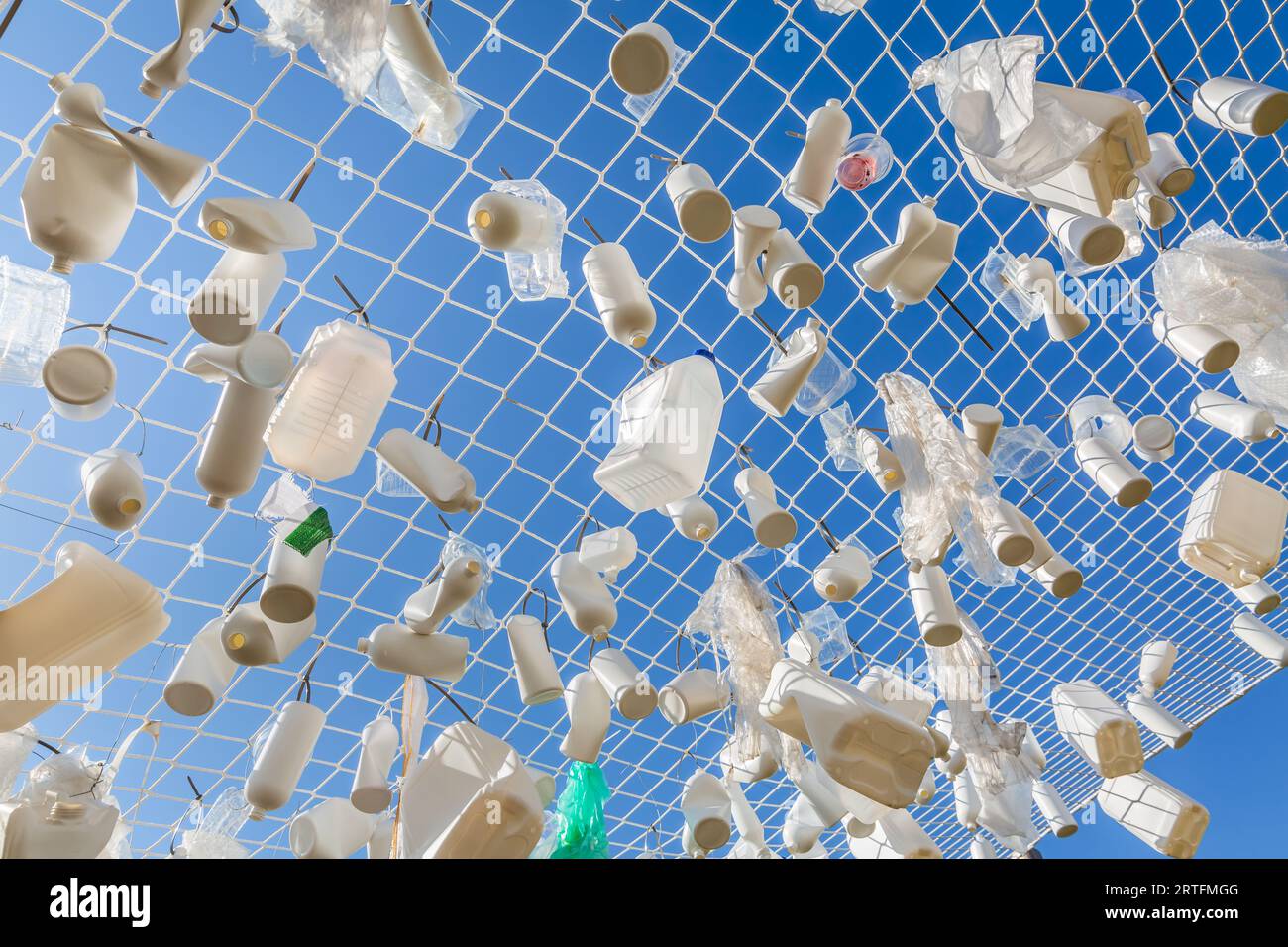 Contenitori di plastica nella rete da pesca contro il cielo blu - concetto di spazzatura, inquinamento idrico, problema ambientale Foto Stock
