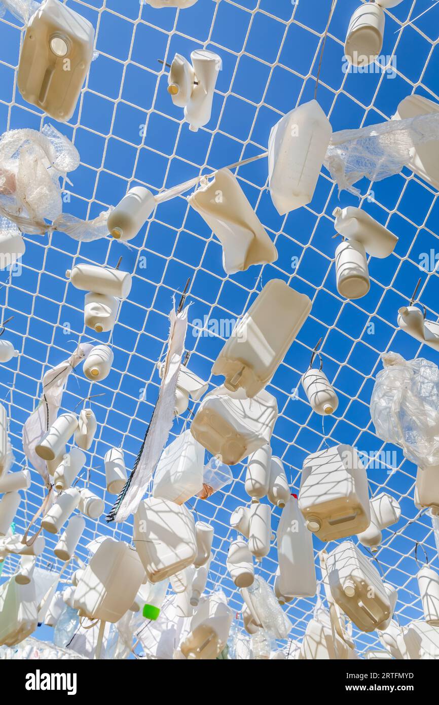 Contenitori di plastica nella rete da pesca contro il cielo blu - concetto di spazzatura, inquinamento idrico, problema ambientale Foto Stock