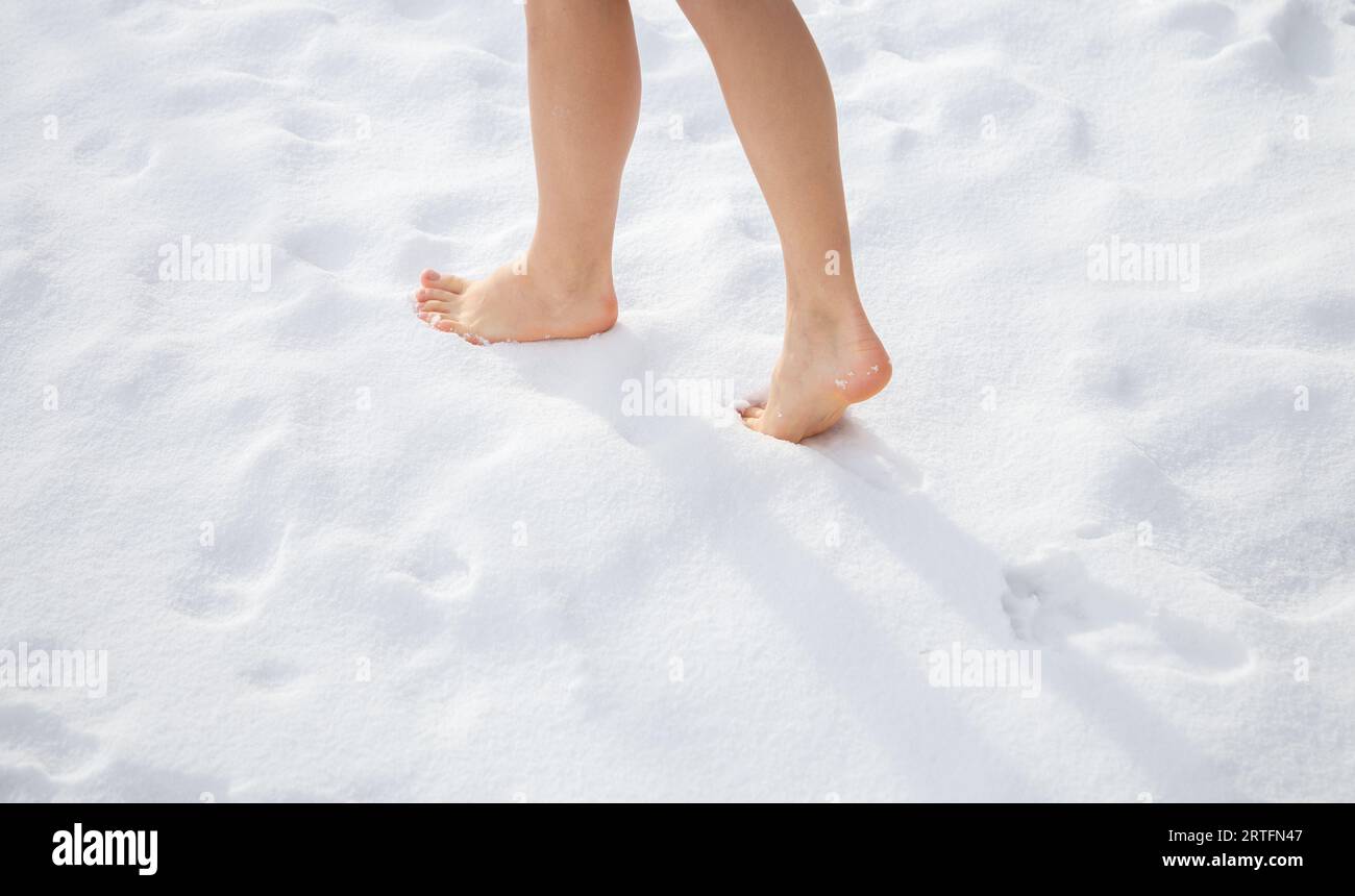 I bellissimi piedi delle donne camminano scalzi sulla neve appena caduta. Concetto di stile di vita sano. Temperarsi nella stagione fredda, aumentare l'immunità nel W Foto Stock