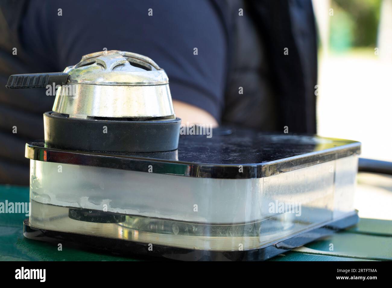 Un uomo fuma un narghilè su una montagna a Bukovel in estate al sole al tavolo, fumando un narghilè, rilassandosi Foto Stock