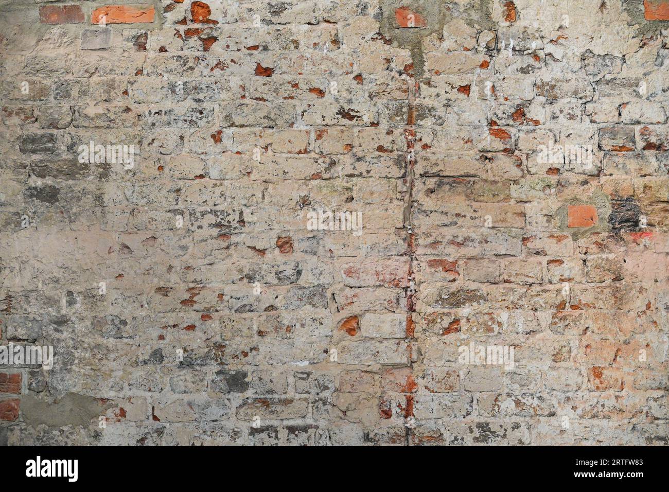 vecchio muro di mattoni rossi con intonaco beige e residui di vernice come texture di sfondo, urbano, concetto di architettura storica, spazio di copia, soft focus selezionato Foto Stock
