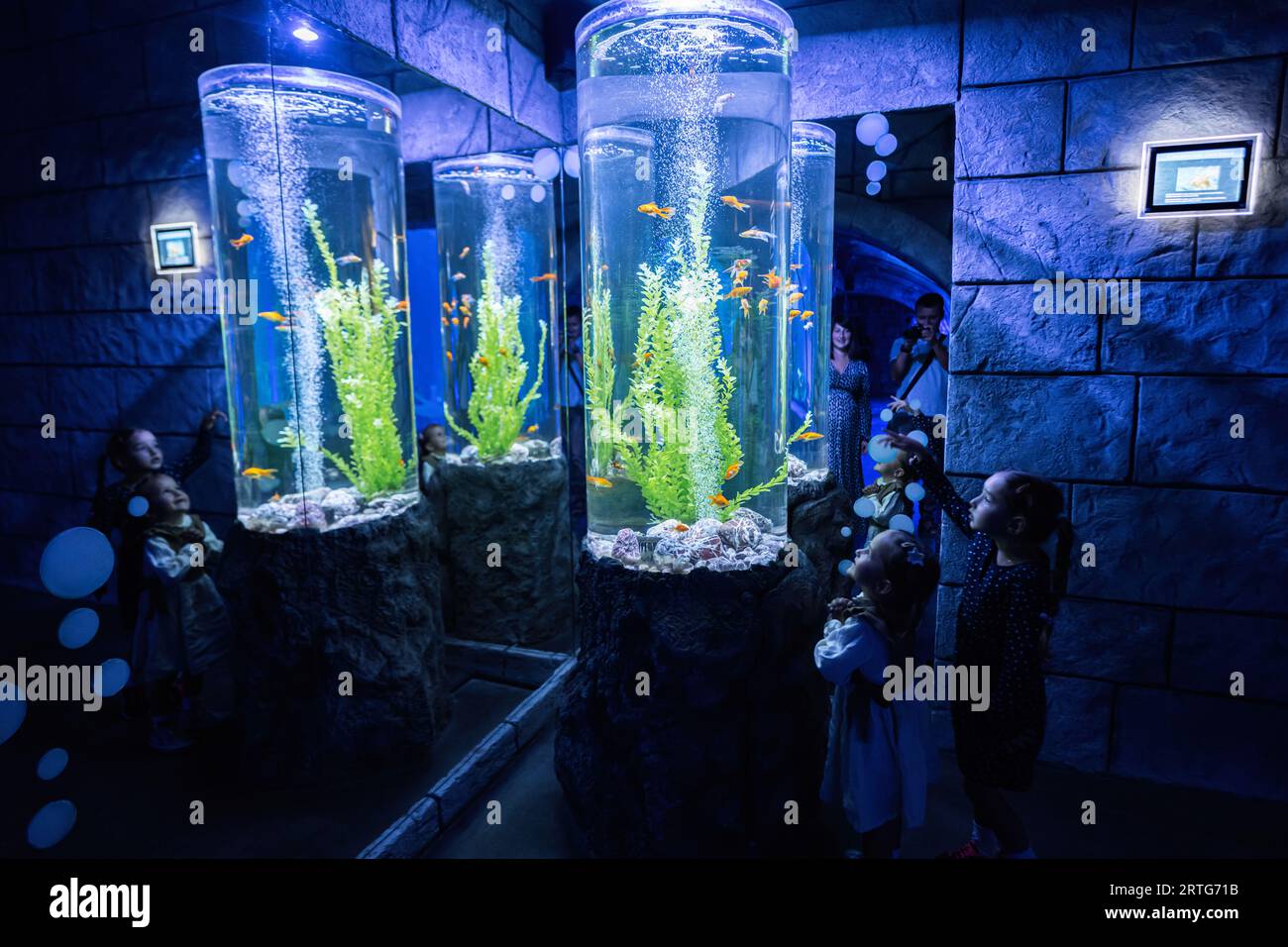 Famiglia che guarda pesci e tartarughe nell'oceanarium. Madre con bambini che si divertono nella vasca espositiva oceanica. Foto Stock