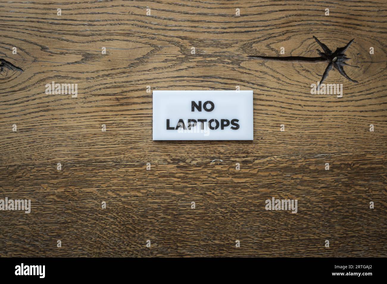 Tavolo in legno con cartello No laptop. Nel caffè urbano non c'è la zona wi-fi. Superficie in legno duro con segnale di restrizione. Stile di vita moderno. Firma con le parole No laptop. Foto Stock