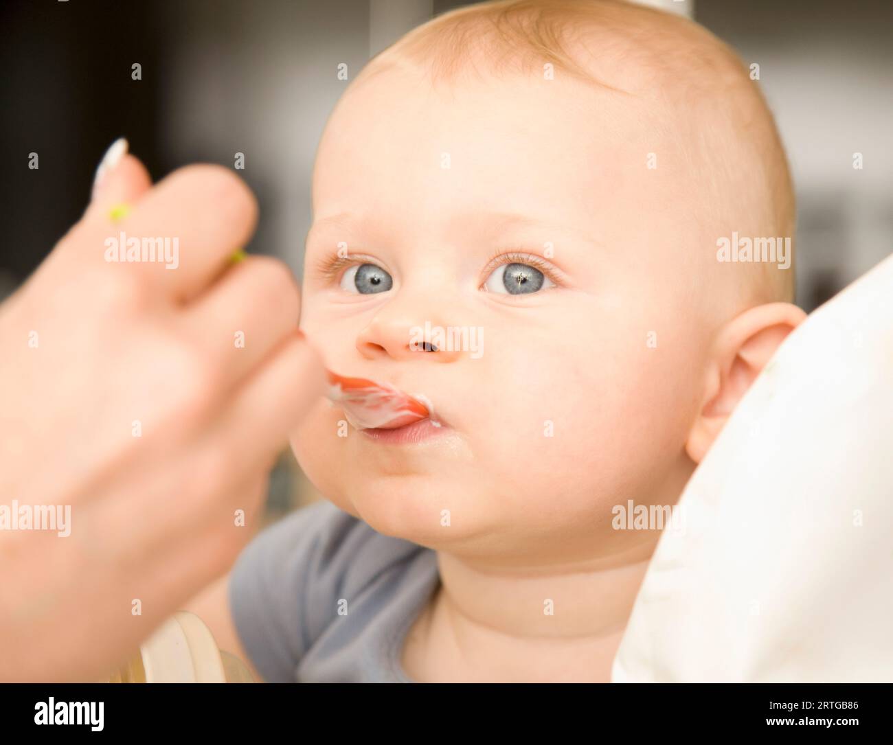 Stretta di mano donna bionda alimentazione baby boy Foto Stock