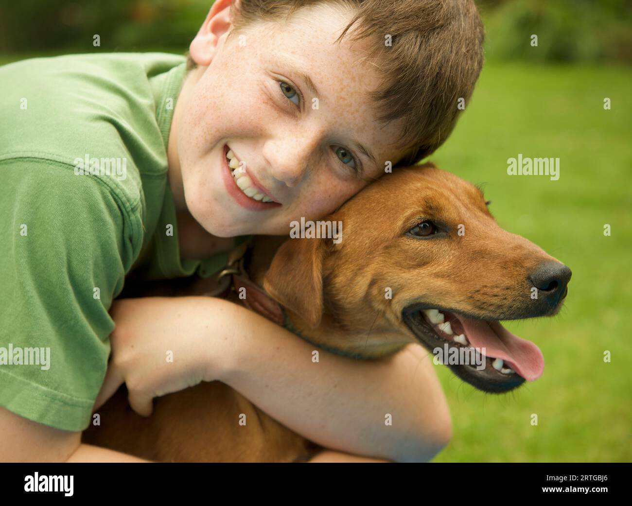 Giovane ragazzo sorridente che abbraccia il suo cane Foto Stock