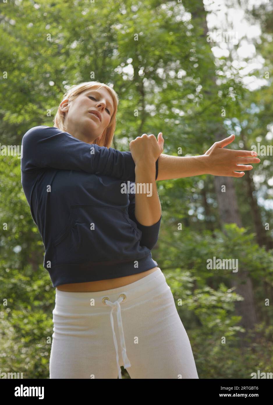 Giovane donna in piedi in una foresta stretching il suo braccio Foto Stock