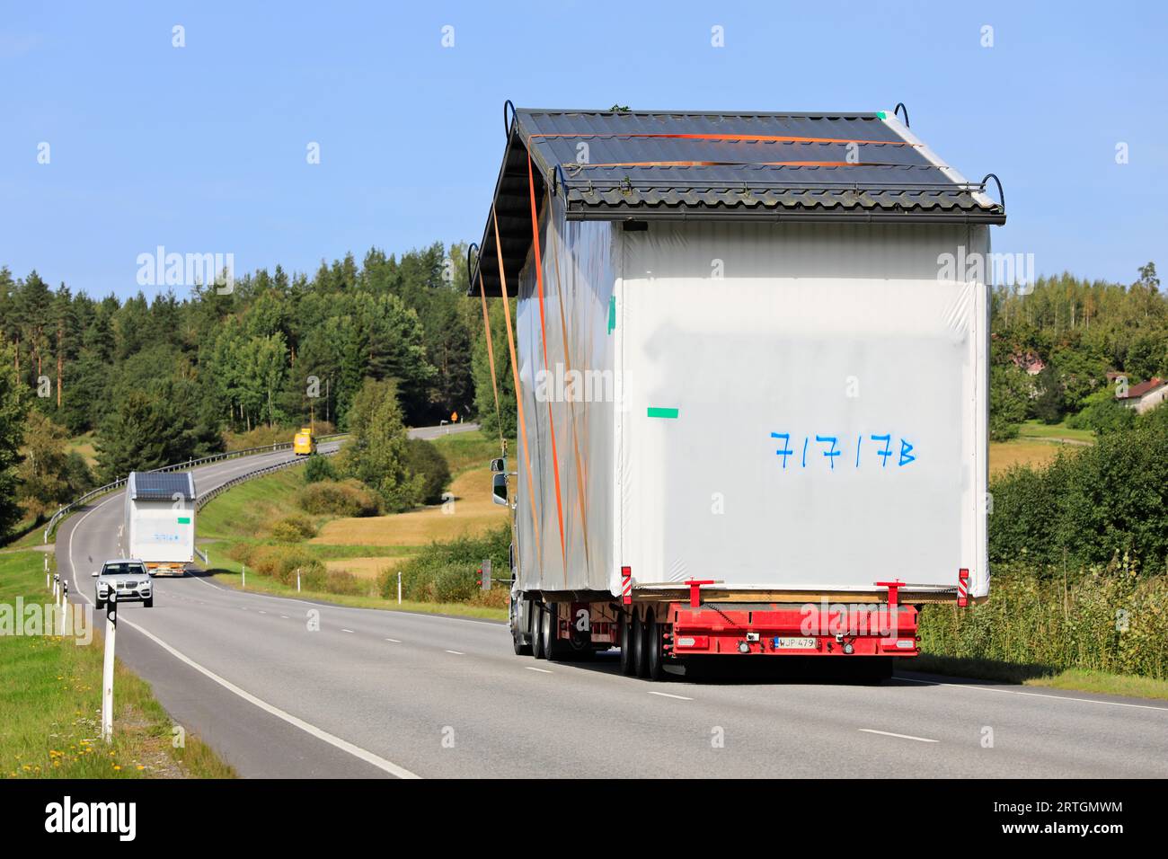 Due eccezionali trasporti di carico che trasportano cabine prefabbricate nel traffico autostradale, assistendo il pilota del veicolo. Salo, Finlandia. 7 settembre 2023. Foto Stock