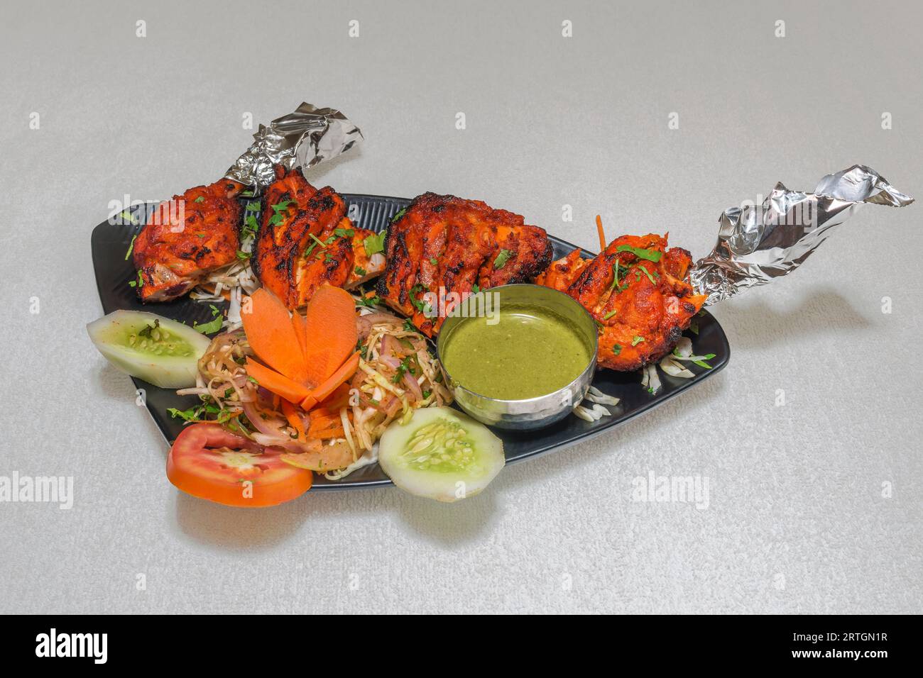 Pollo tenero e succoso Tandoori servito con chutney alla menta e insalata piccante Foto Stock