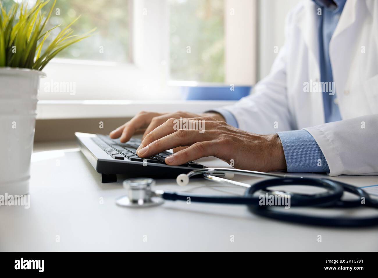 medico che digita sulla tastiera del computer. lavoro in ambulatorio. consultazione medica online e concetto di e-health Foto Stock