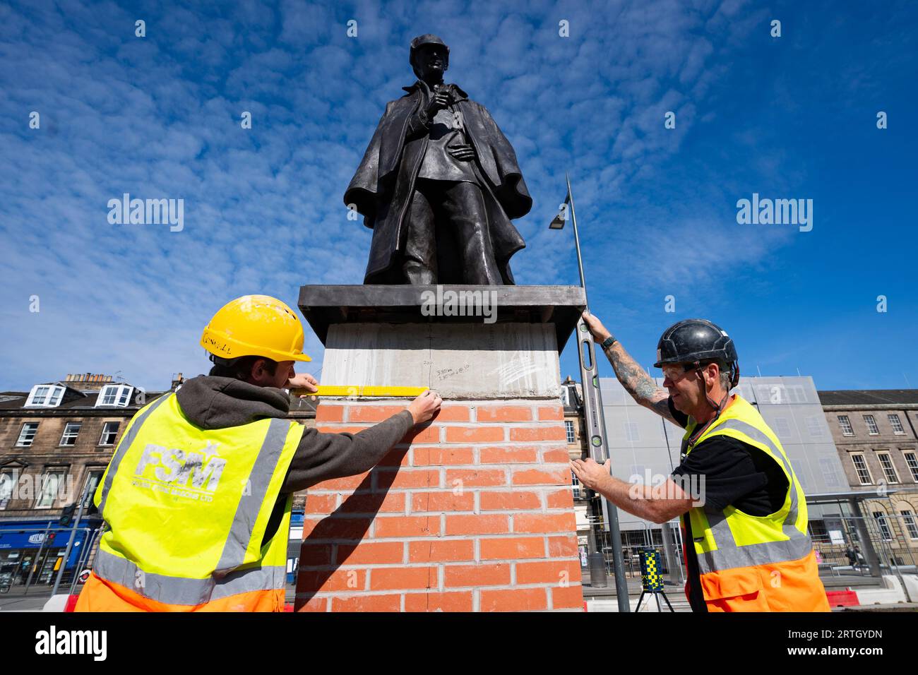 Edimburgo, Scozia, Regno Unito. 9 settembre 2023. La statua recentemente rinnovata di Sherlock Holmes è stata presentata oggi in una nuova posizione in Piccardy Place dalla parente di Sir Arthur Conan Doyle, Tania Henzell e dal Consigliere dei trasporti Scott Arthur. Segnando il vicino luogo di nascita del creatore del super-sleuth, Sir Arthur Conan Doyle, la scultura in bronzo a grandezza naturale fu rimossa nel 2018 mentre i tram per Newhaven furono eseguiti. È stato ristrutturato dalla Black Isle Bronze a Nairn. PIC; gli operai apportano i ritocchi finali alla base che regge la statua. Iain Masterton/Alamy Live News Foto Stock