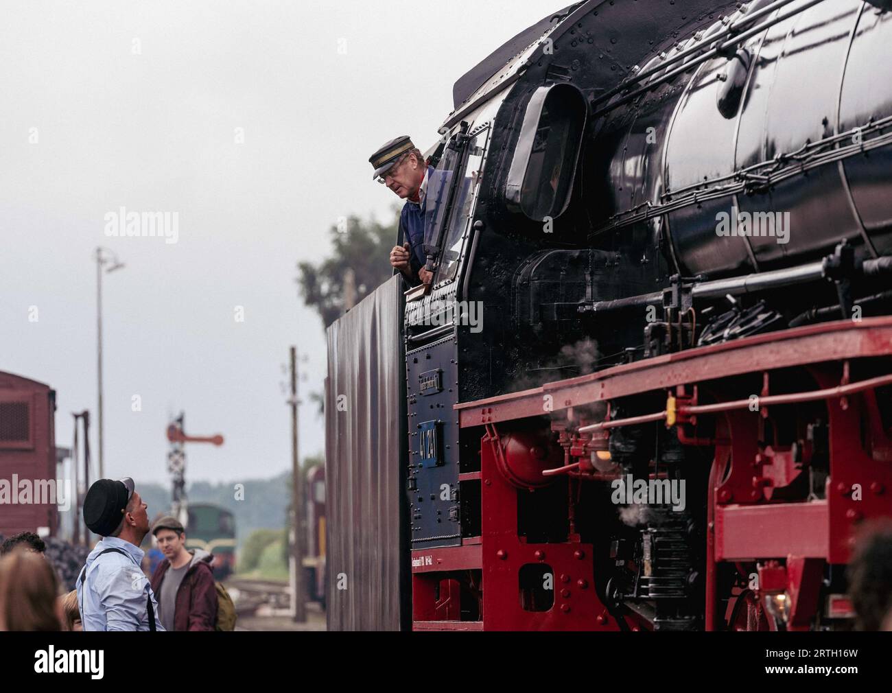 Beekbergen, Paesi Bassi - 6 agosto 2023: Ingegneri di un classico treno a vapore che chiacchierano prima dell'inizio di un viaggio. Foto Stock