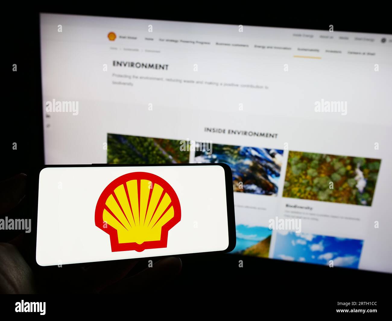 Persona che possiede uno smartphone con il logo della società britannica di petrolio e gas Shell plc sullo schermo di fronte al sito Web. Concentrarsi sul display del telefono. Foto Stock