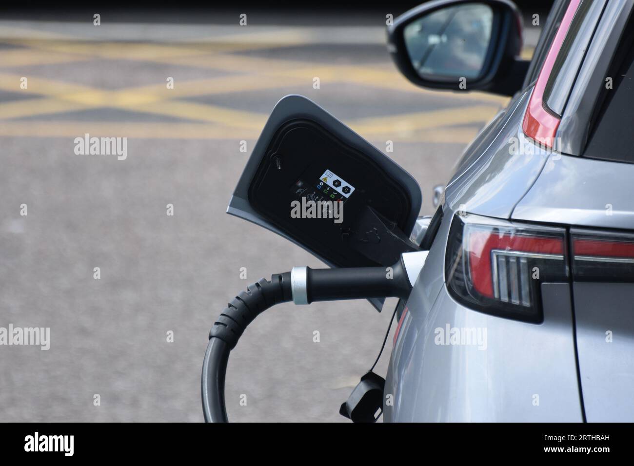 Una presa di ricarica e un cavo di un veicolo elettrico che viene ricaricato presso una stazione di servizio autostradale di Exeter, Regno Unito Foto Stock