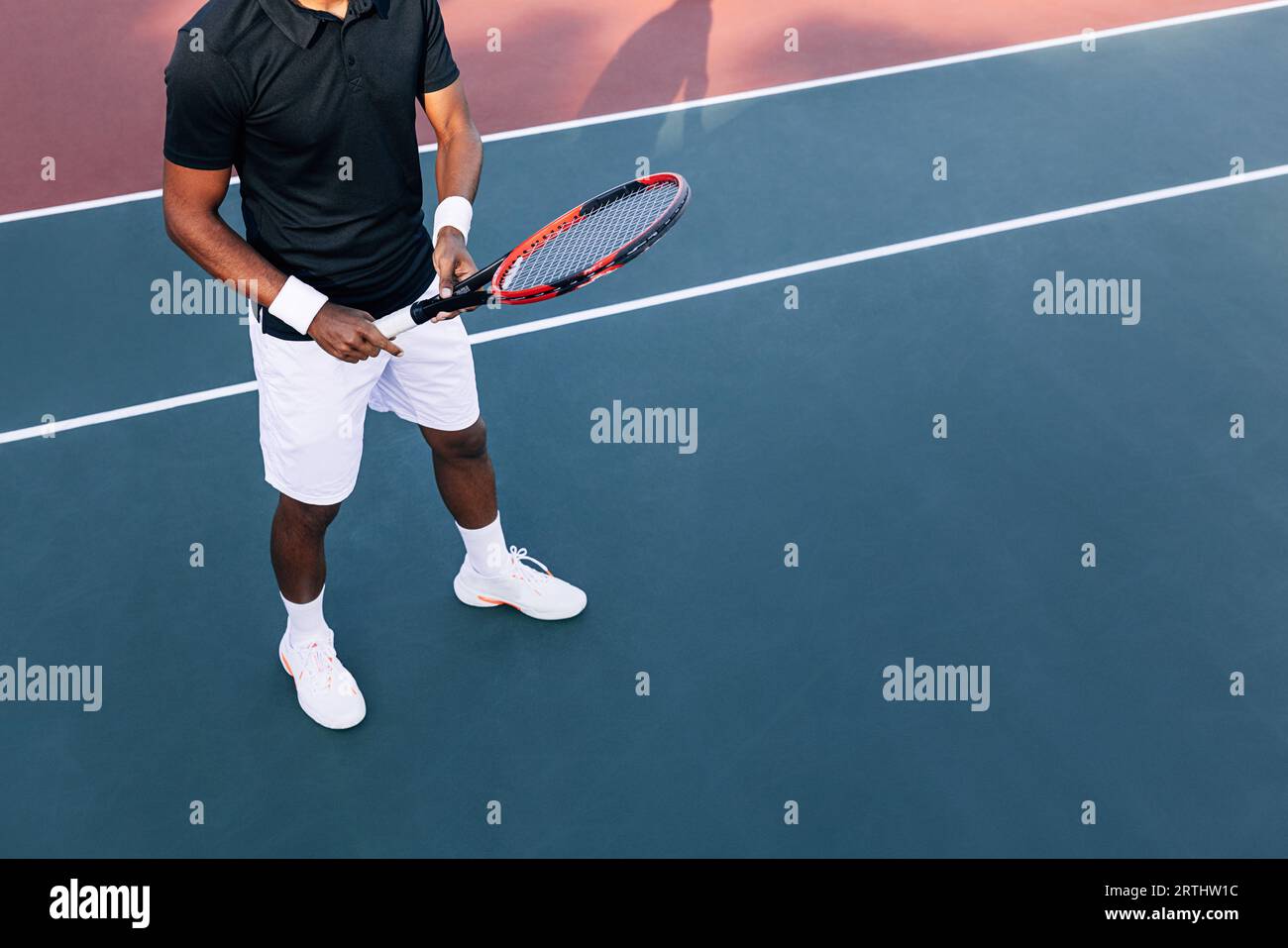 Tennista irriconoscibile con abiti sportivi in piedi su un campo duro che tiene una racchetta Foto Stock