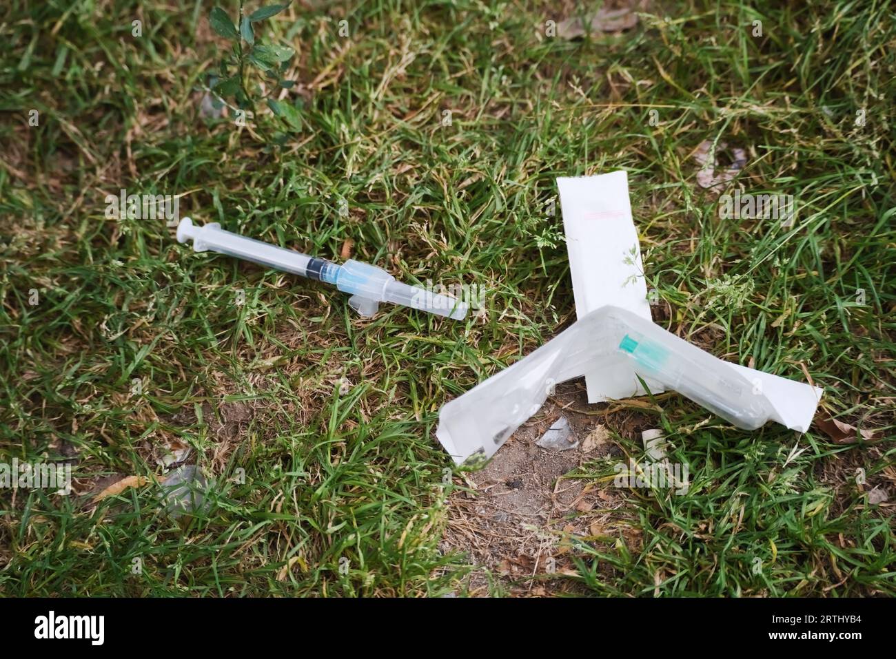 Ago di sicurezza usato scartato nell'erba del parco cittadino da un tossicodipendente per via endovenosa Foto Stock