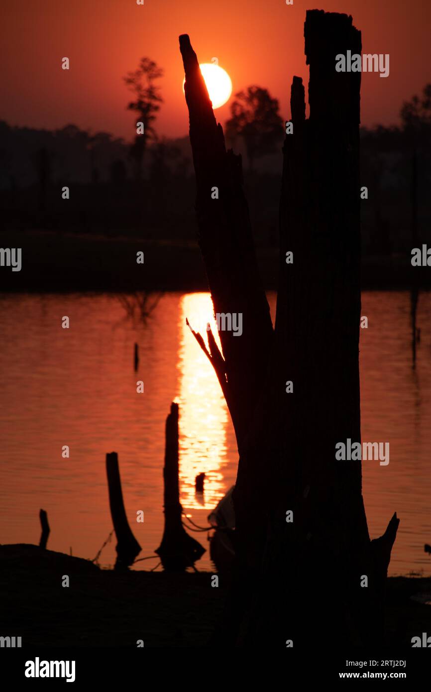 Cieli arancioni e tramonti sugli alberi morti sommersi nel fiume Nam Theun a Thalang, Konglor loop, Thakhek, Laos Foto Stock