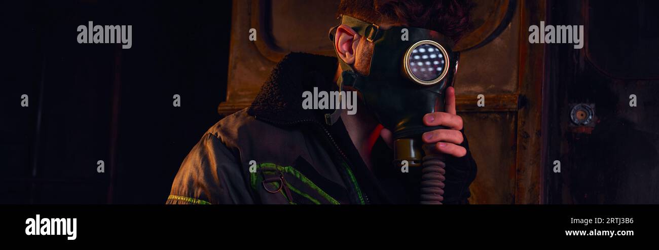 uomo in maschera antigas e giacca indossata in tunnel sotterraneo scuro, concetto post-disastro, banner Foto Stock