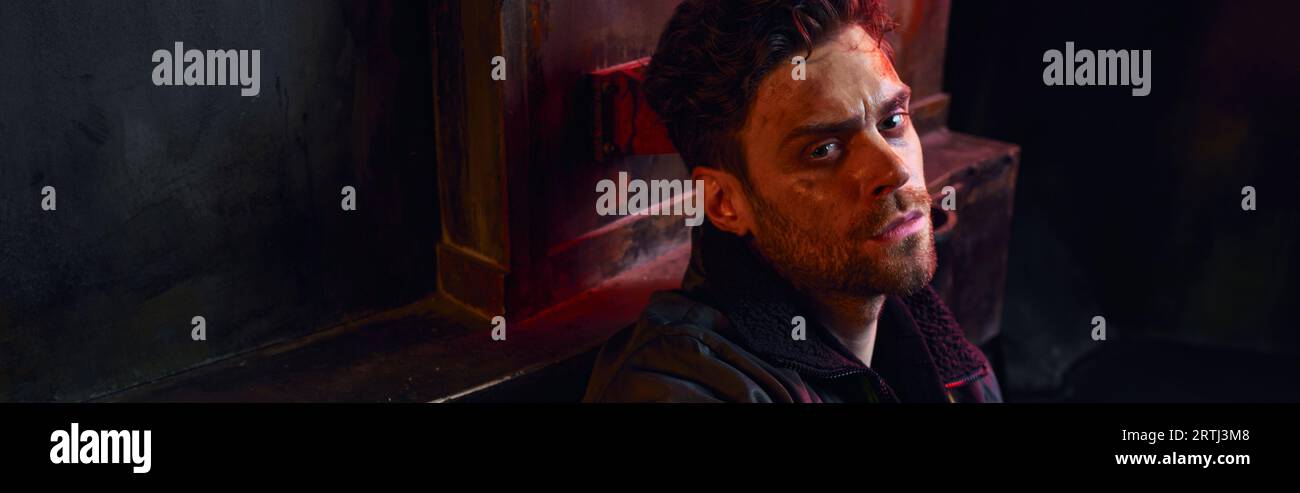 ritratto di un uomo premuroso con un volto non rasato e ferito nell'oscurità della metropolitana post-disastro, banner Foto Stock
