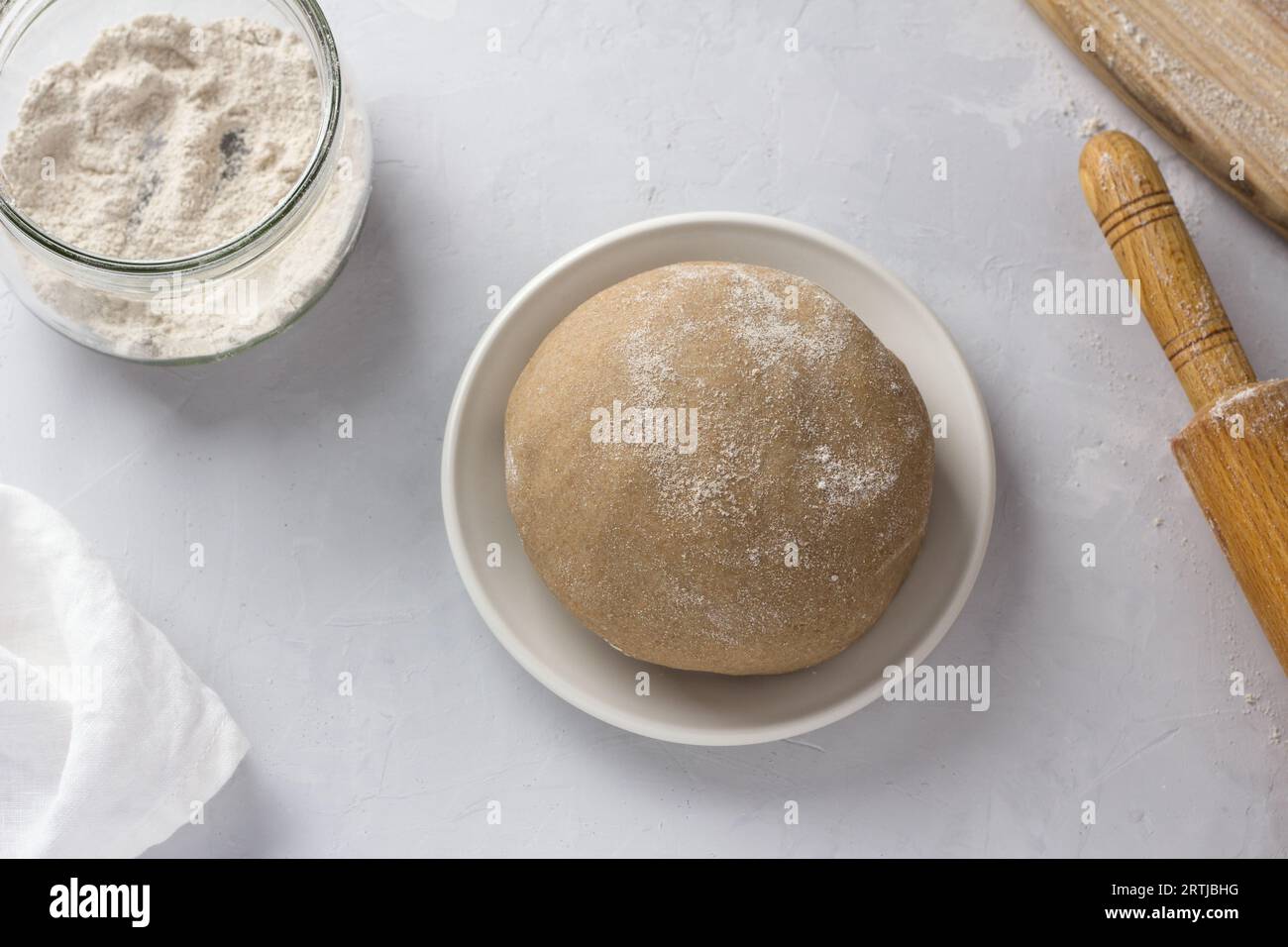 Impasto di segale per torte, farina di segale e mattarello su sfondo grigio, vista dall'alto. Fase di cottura. Foto Stock