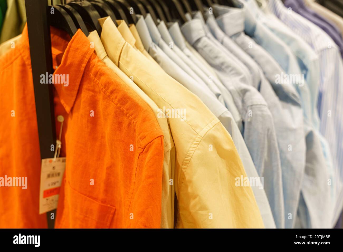 Le luminose maglie da uomo con maniche lunghe sono appese ad appendiabiti in un negozio di abbigliamento. Primo piano. Foto Stock