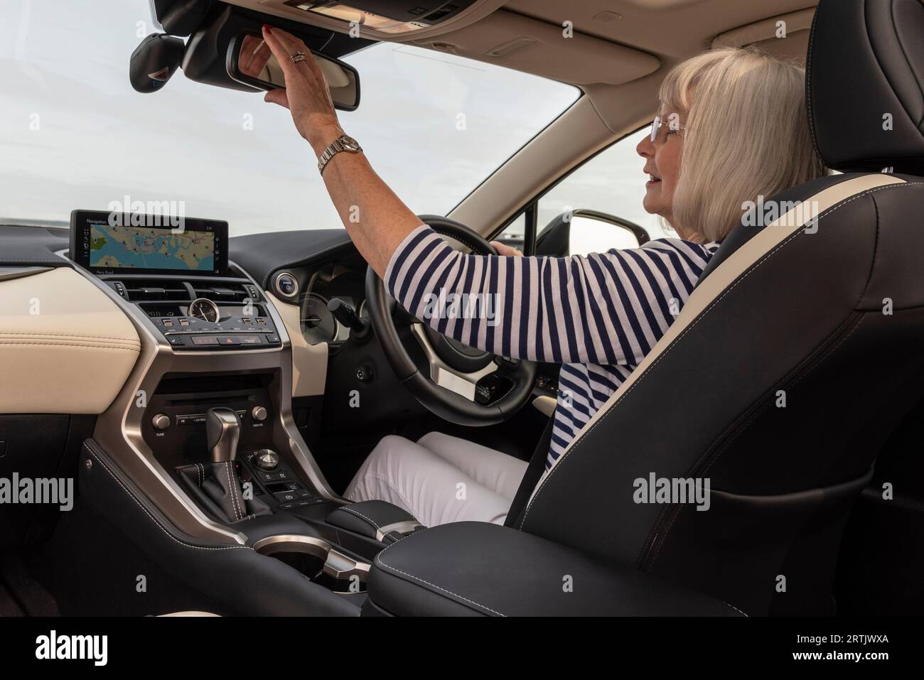 Portsmouth, Inghilterra, Regno Unito. 29 agosto 2023. Donna conducente che regola lo specchietto retrovisore prima di partire a bordo di un'auto di lusso. Foto Stock