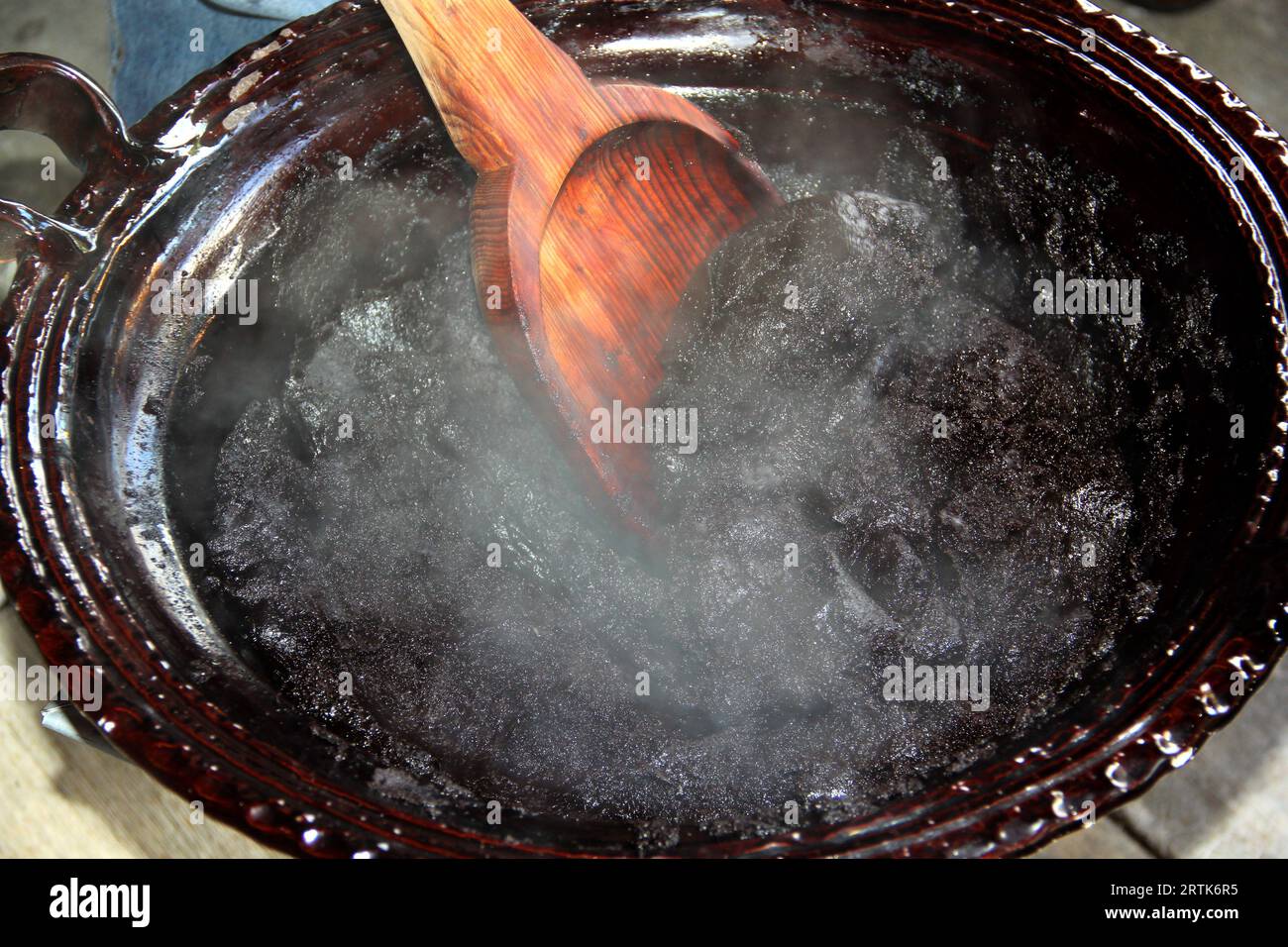 Preparazione della talpa rossa, un tipico piatto messicano in una pentola di argilla con un gigantesco cucchiaio di legno sul fuoco di una stufa con tutti gli ingredienti integrati Foto Stock