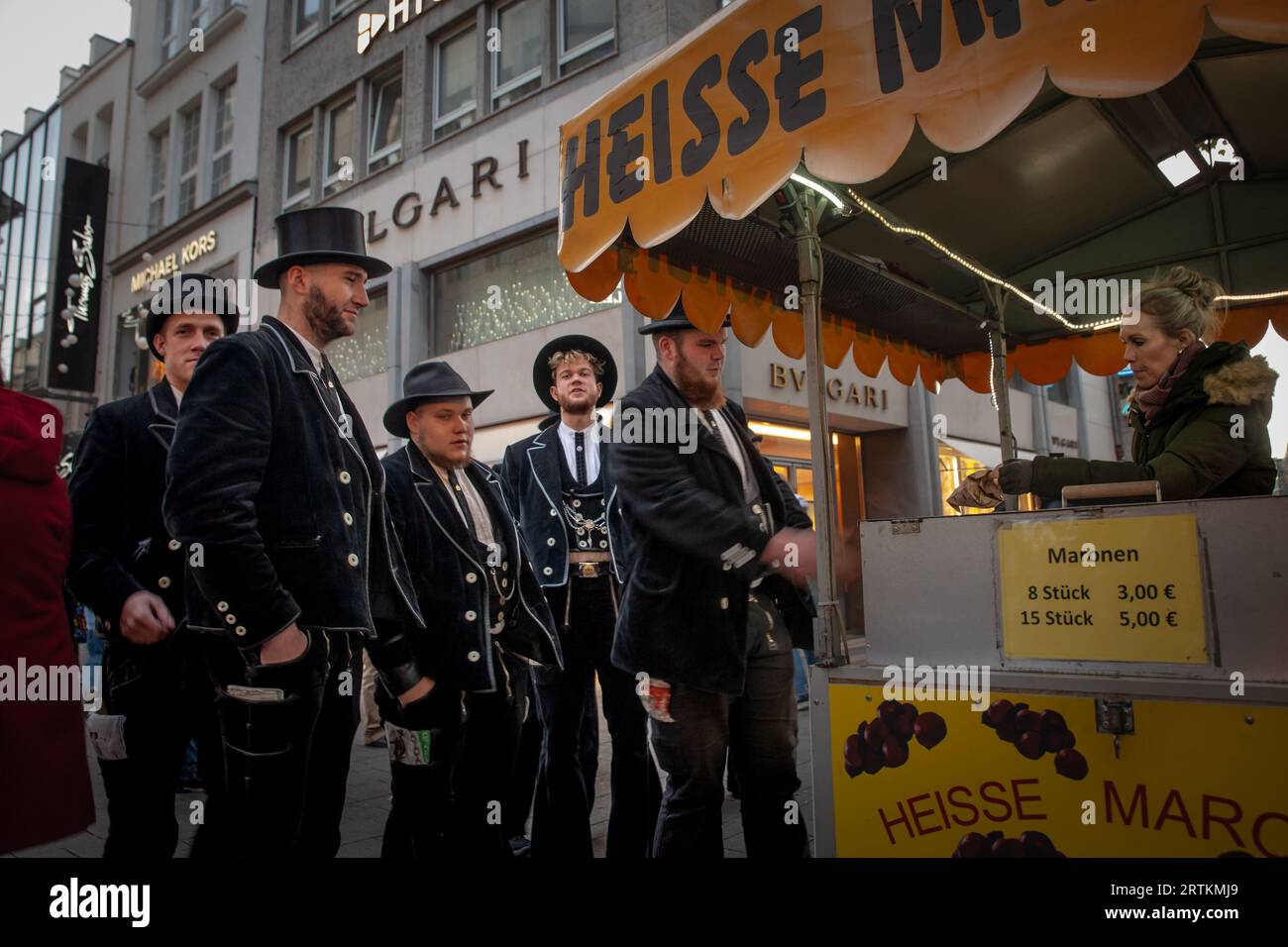 Foto di persone vestite in costume per il Carnevale di Colonia in piedi e che mangiano castagne arrosto a Colonia, in Germania. Il Carnevale di Colonia (tedesco: Kö Foto Stock