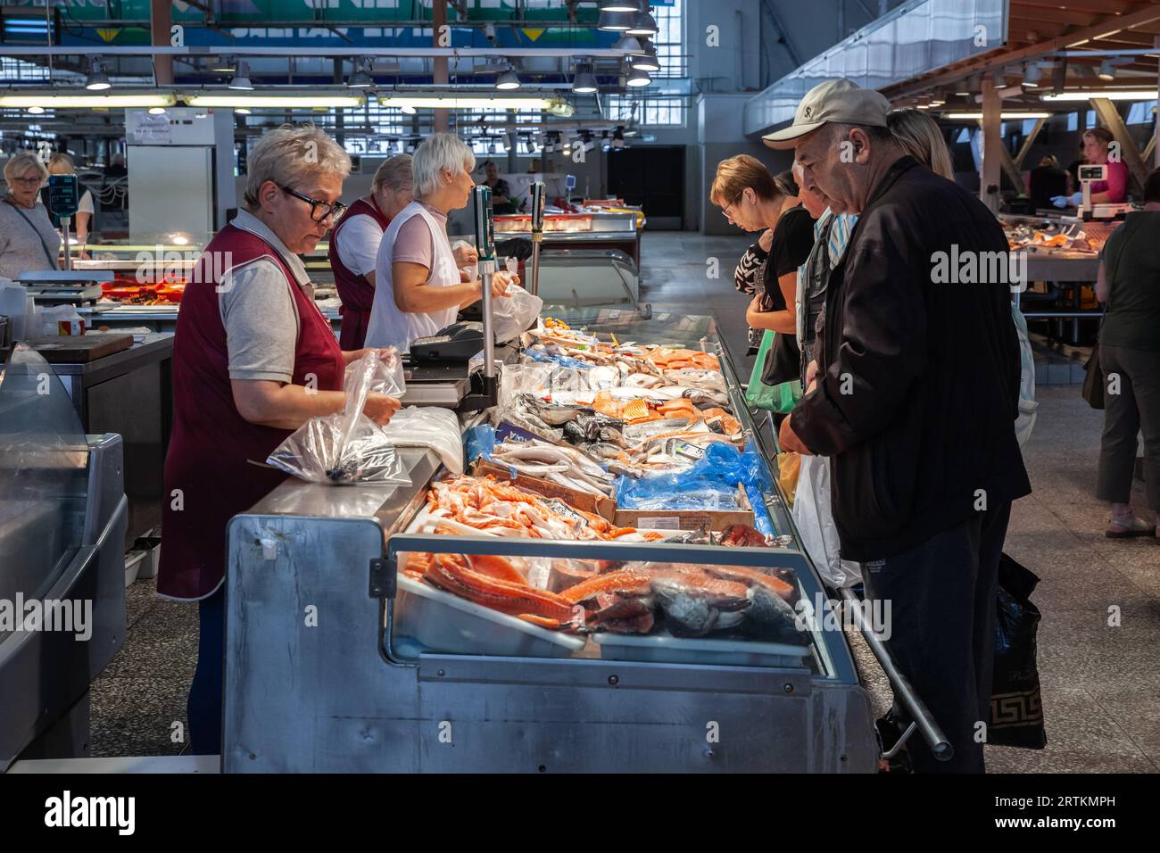 Immagine di un gruppo di persone che discutono e acquistano pesce da un pescivendolo di centraltirgus a riga, in lettonia. Riga Central Market è il marchio più grande d'Europa Foto Stock