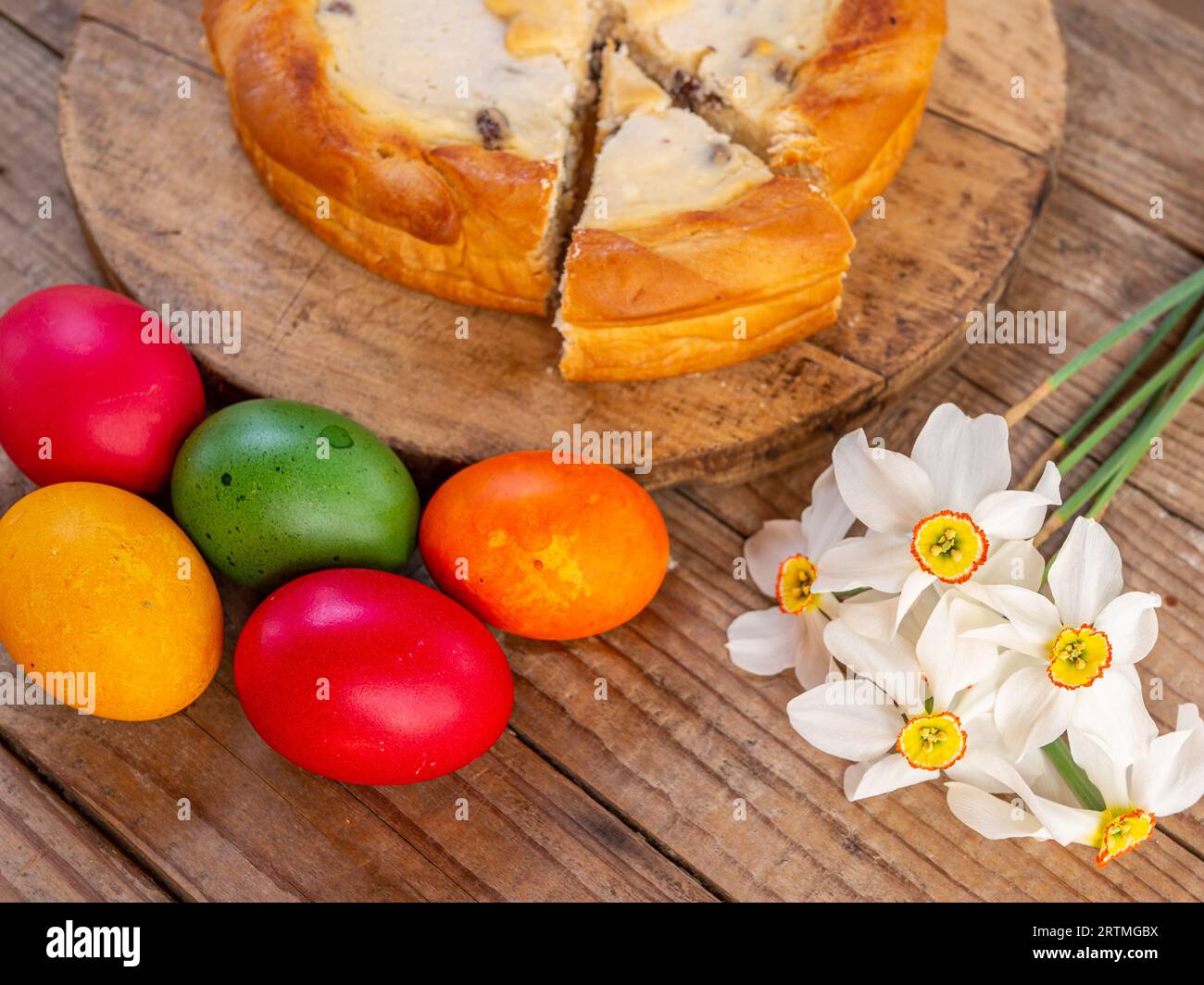 tradizionale piatto pasquale rumeno, cozonac e pasca, o dolce e torta di formaggio come su un tavolo di legno e uova di pasqua colorate e fiori a parte Foto Stock