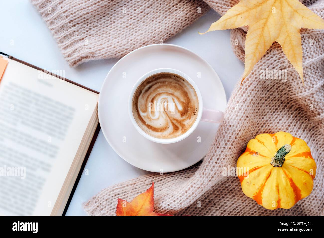 Caffè caldo in una tazza, un libro aperto, zucca gialla e foglie autunnali. Vista dall'alto, base piatta. Concetto di autunno. Foto Stock