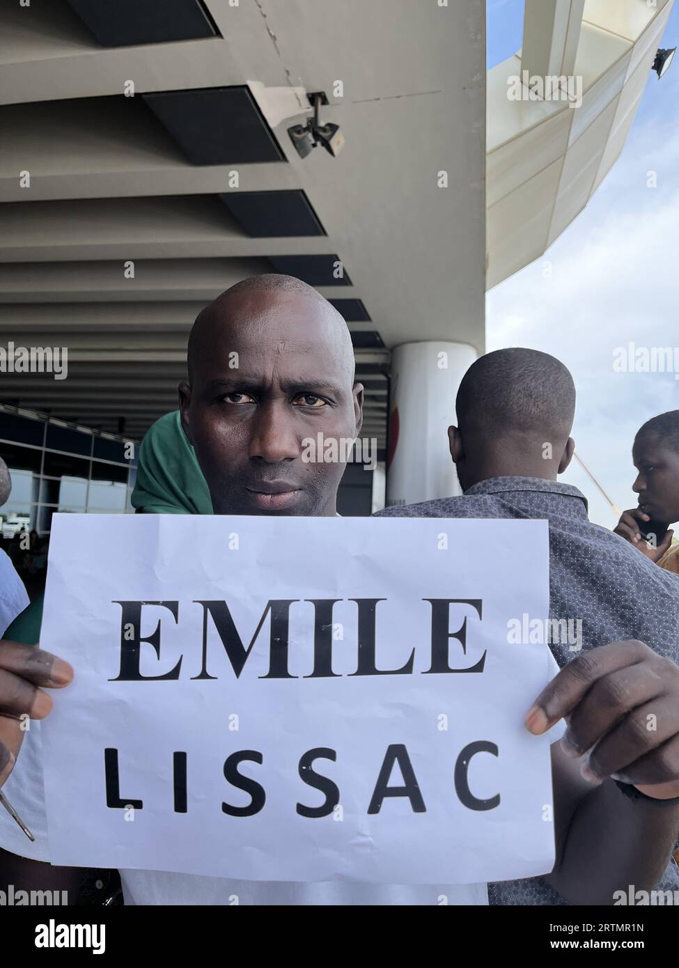 Autista con un foglio di carta con il nome del cliente fuori dall'aeroporto Blaise Diagne, Senegal Foto Stock