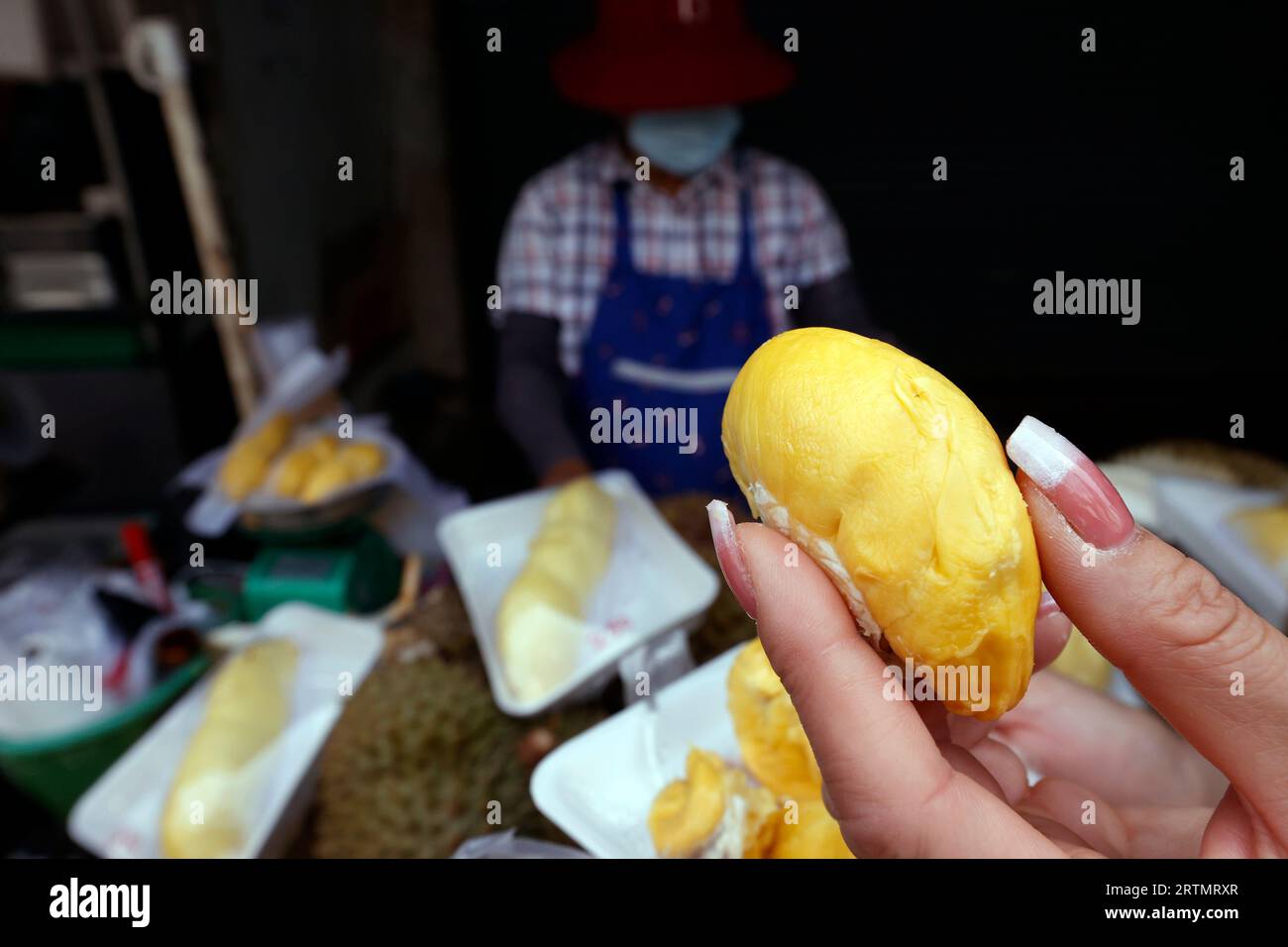 Una donna prepara Durian Fruit per la vendita. Le bancarelle di Street food sono popolari sia tra i turisti che tra la gente del posto. Bangkok. Thailandia. Foto Stock