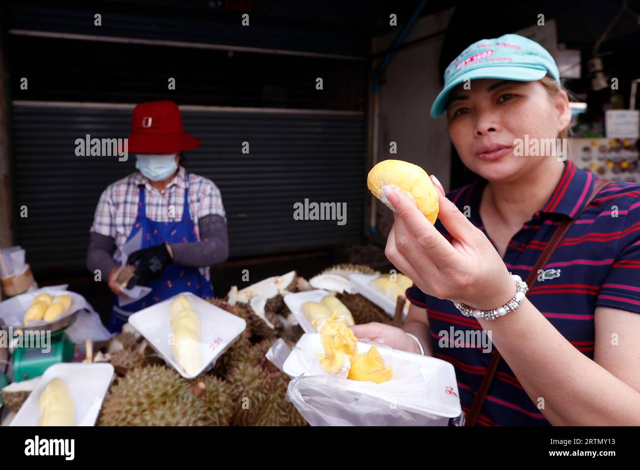 Una donna prepara Durian Fruit per la vendita. Le bancarelle di Street food sono popolari sia tra i turisti che tra la gente del posto. Bangkok. Thailandia. Foto Stock