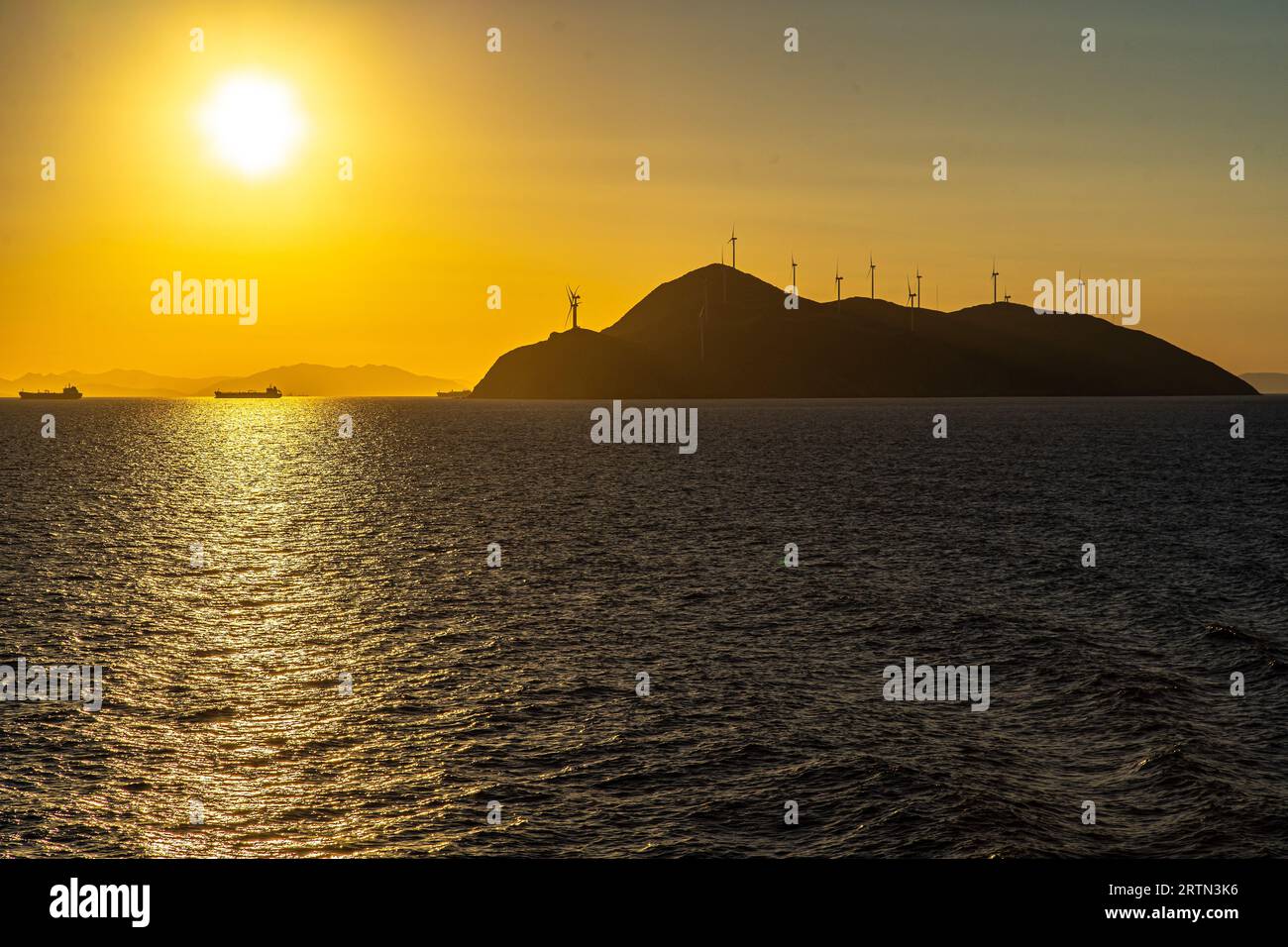 L'isola di Agios Georgios e le sue turbine eoliche all'ingresso del golfo Saronico, Grecia, viste da una barca di passaggio Foto Stock