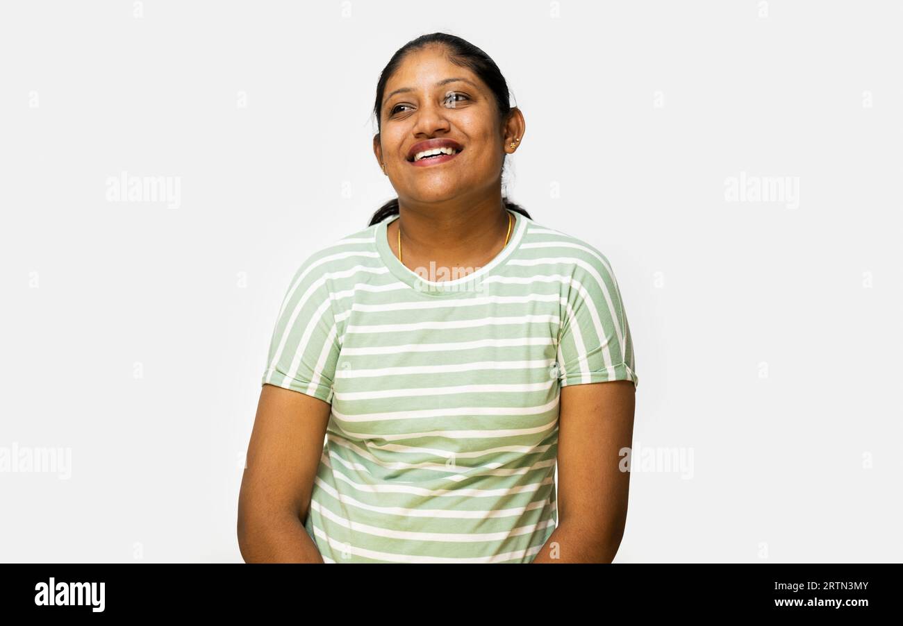 Una donna felice che ride e sorride di fronte a uno sfondo bianco. Indossa un abito casual e si fa tirare i capelli in coda di cavallo. Foto Stock