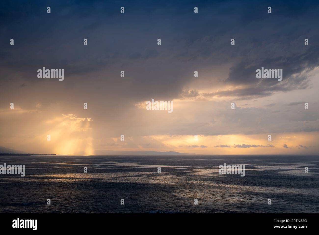 Paesaggio al tramonto tra le nuvole sull'orizzonte del mare. Riflessi dorati nelle nuvole e nel mare. Foto Stock