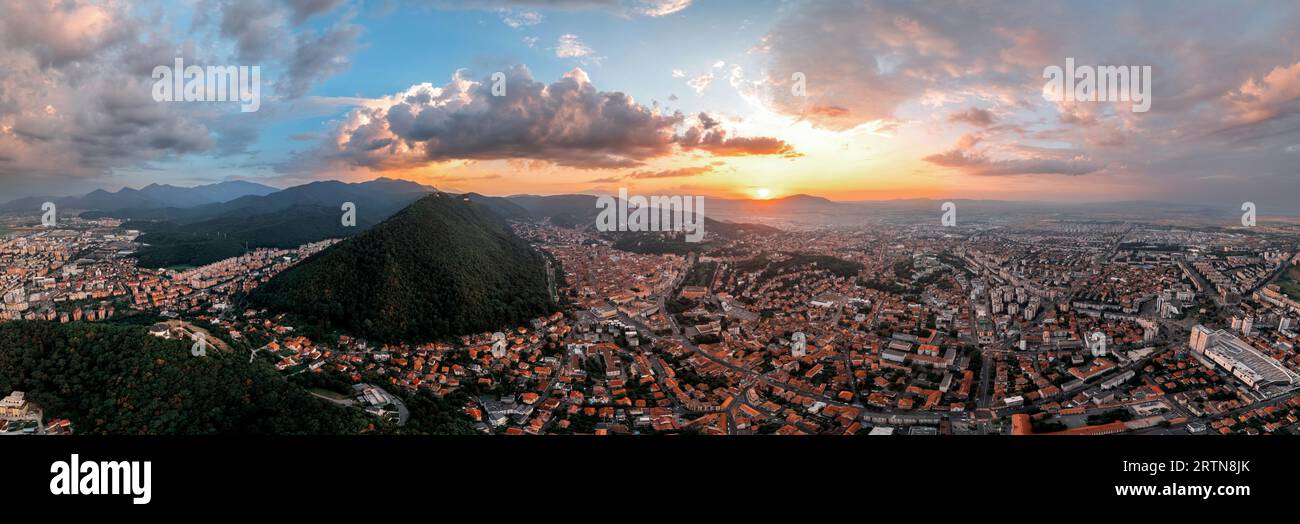 Vista panoramica aerea di Brasov al tramonto, Romania. Centro storico con edifici antichi, colline ricoperte di verde Foto Stock