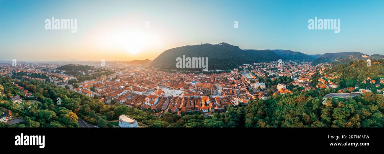 Vista panoramica aerea di Brasov all'alba, Romania. Centro storico con edifici antichi, colline ricoperte di verde Foto Stock