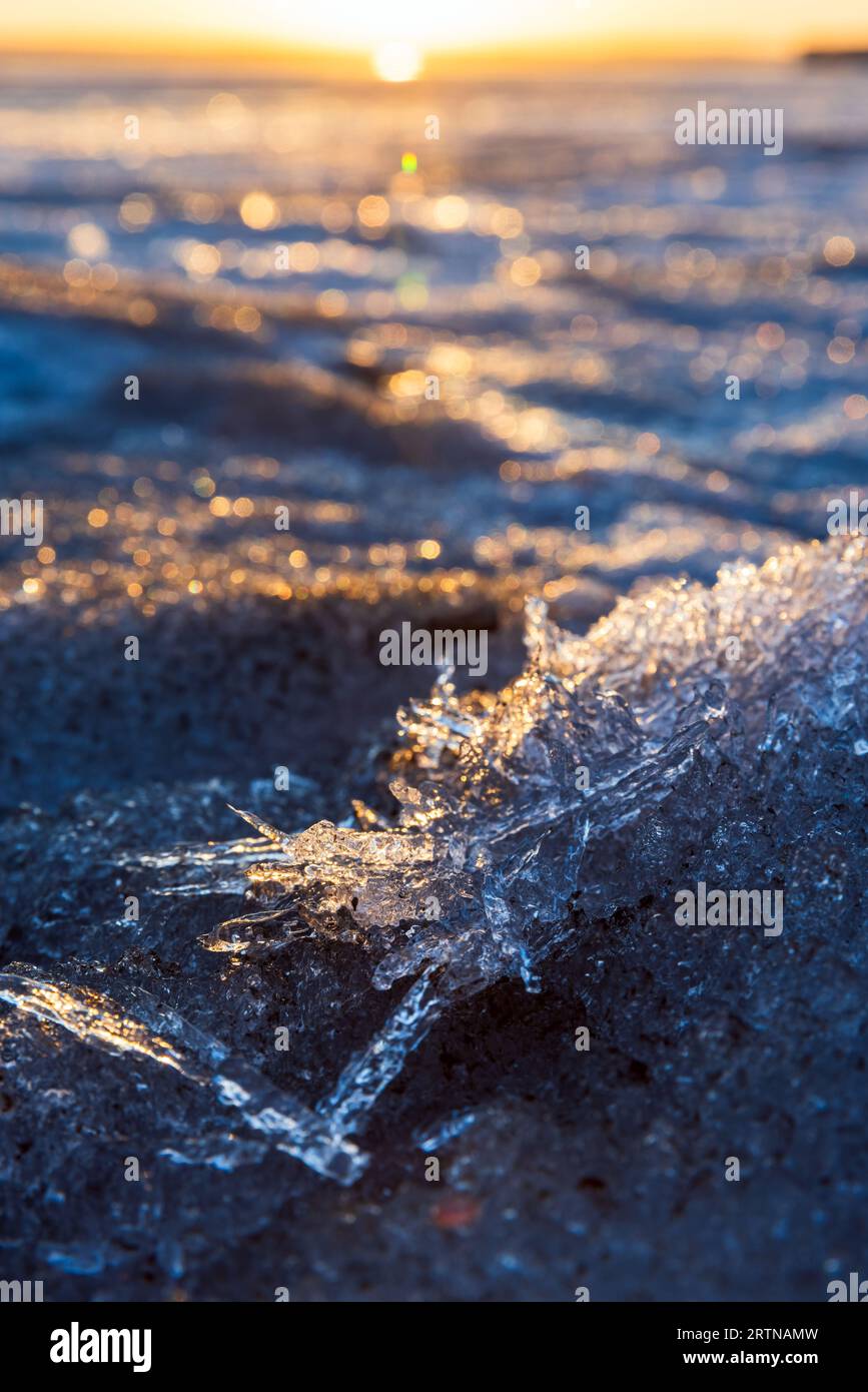 Paesaggio invernale con acqua di lago ghiacciata. Cristalli di ghiaccio alla luce del sole, foto verticale ravvicinata con messa a fuoco morbida selettiva Foto Stock