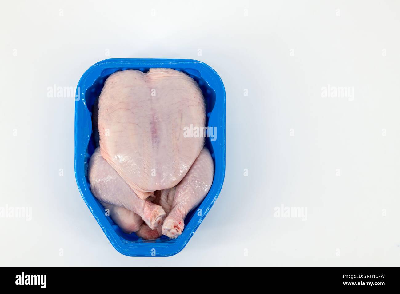 Pollo crudo intero con pelle confezionato in una scatola di plastica e sigillato per la conservazione. Pollo crudo con impacco di pelle per cucinare. Foto Stock