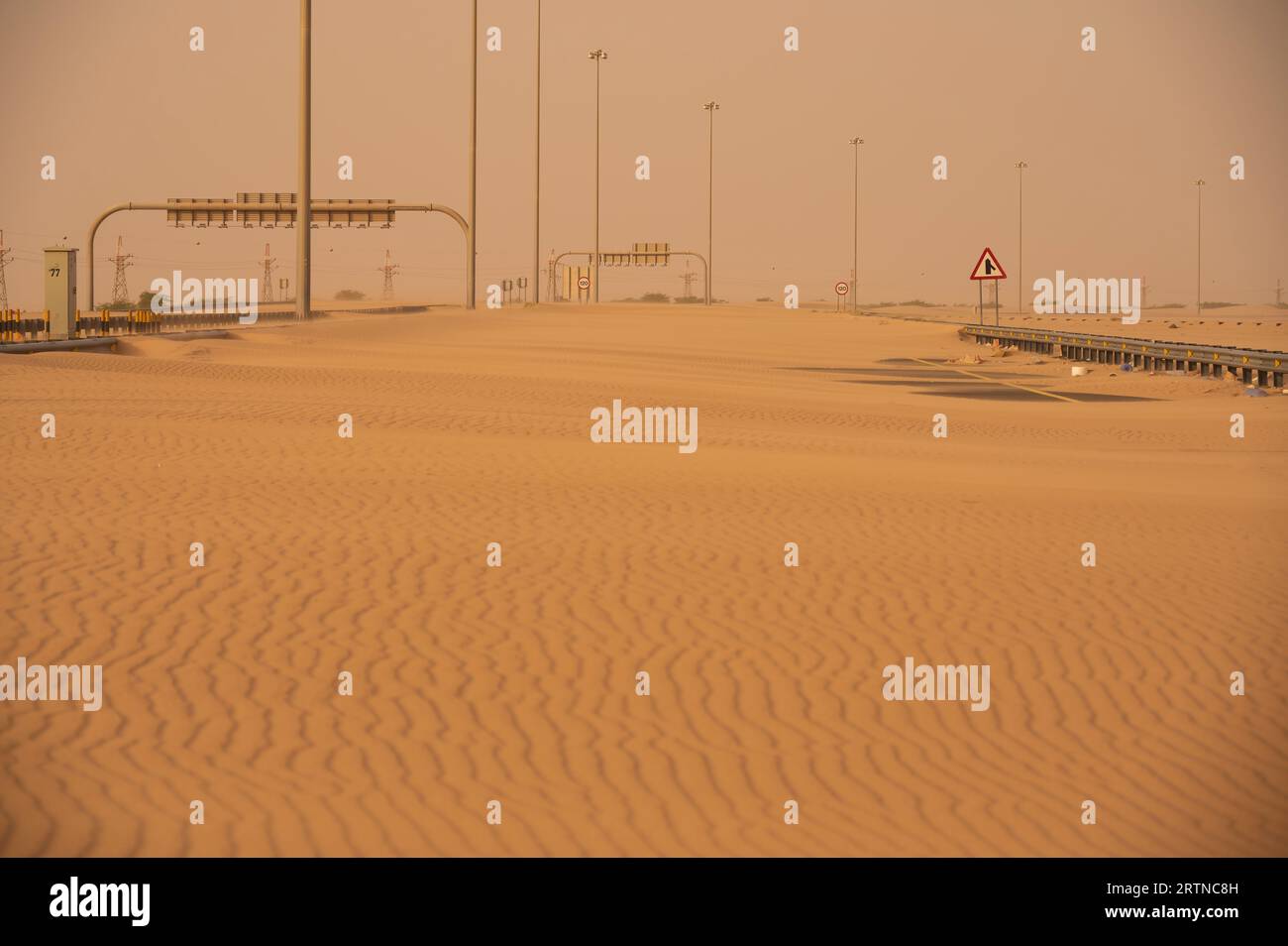 Le strade sono coperte di sabbia desertica dopo una tempesta di sabbia. Non c'è posto per il veicolo che passi la strada. Strada di tempesta di sabbia bloccata dalla sabbia del deserto. Blocco della strada nel deserto Foto Stock