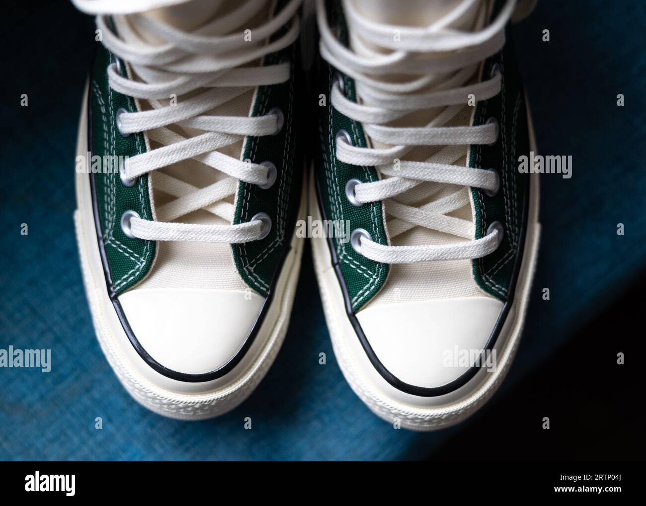 Sneaker da sposa retrò alla moda con lacci e puntali in gomma. Sneaker classiche in verde con sfondo blu. Foto Stock
