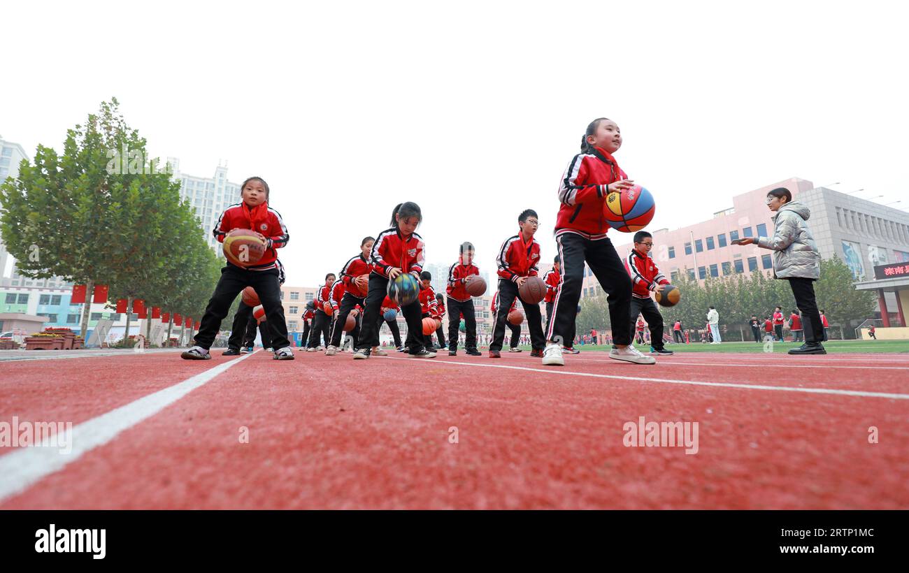 LUANNAN COUNTY, Cina - 3 novembre 2021: Gli studenti delle scuole primarie stanno addestrando le abilità di base di basket in classe, Cina settentrionale Foto Stock