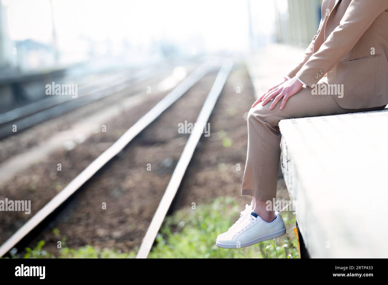 Un uomo seduto sul bordo della piattaforma del treno con spazio per le copie per il testo. Consapevolezza della depressione. Foto Stock