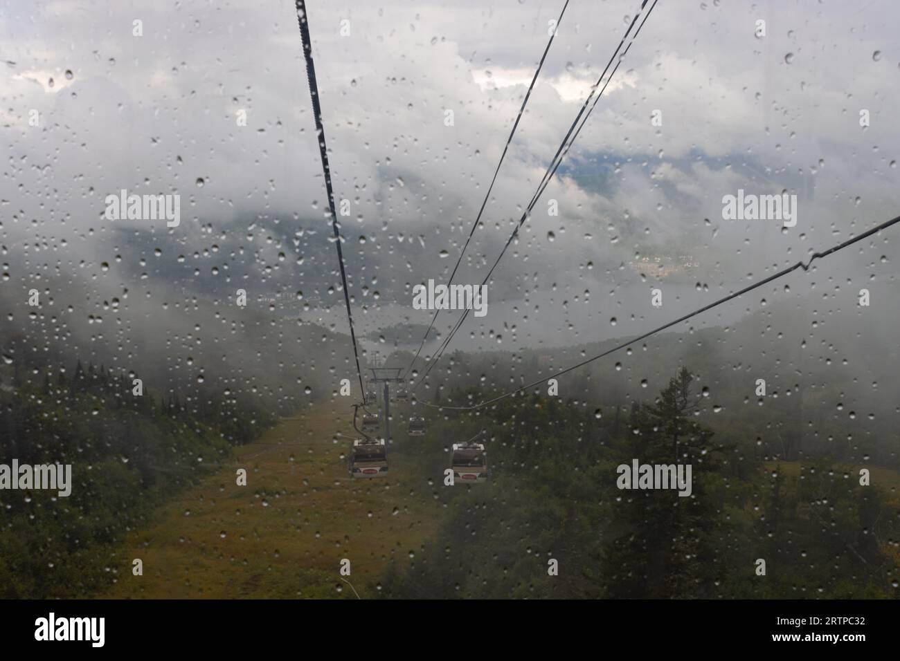La vista attraverso la gondola è oscurata da pioggia, nebbia e graffi; un viaggio attraverso le nuvole Foto Stock