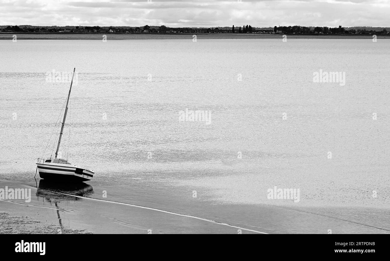 Barca arenata nel mare di Cancale Town in Normandia nel nord della Francia durante la bassa marea con effetto bianco e nero Foto Stock