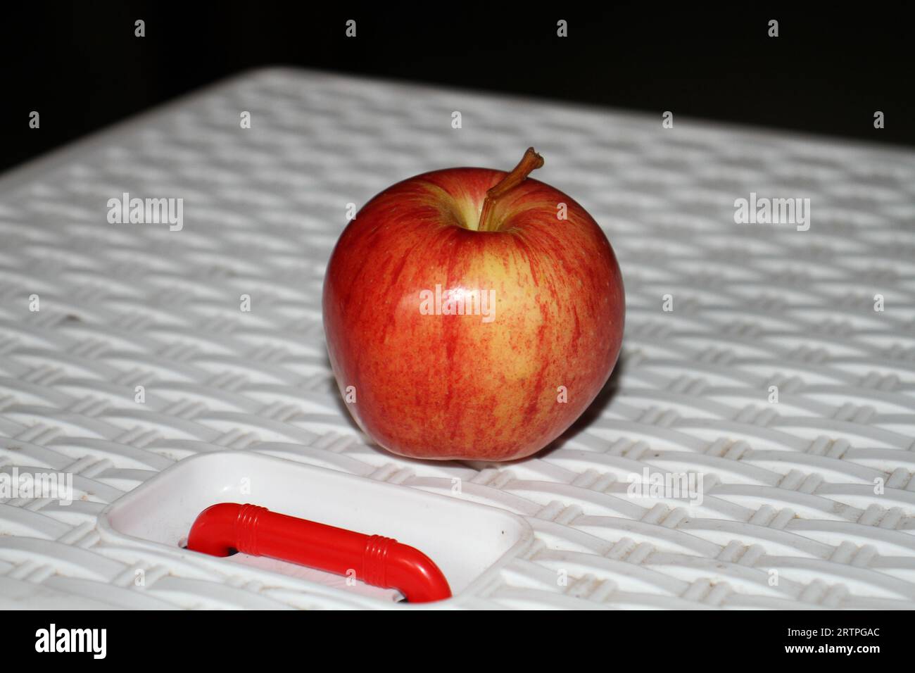 Una mela rossa si trova sulla piattaforma di plastica bianca. Foto Stock